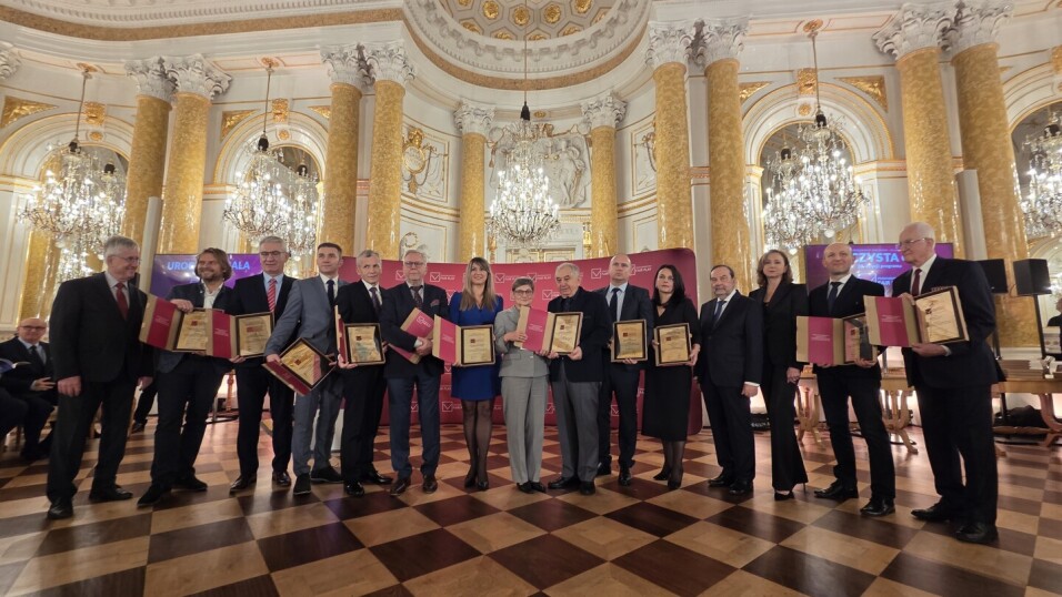 Fair Play 2025  na zdjęciu elegancko ubrane osoby z nagrodami w dłoni pozuja do wspólnego zdjęcia. Widac tez organizatorów. Oraz konferansjera, który prowadził wydarzenie w Zamku Królewskim w Warszawie.