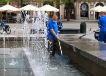 Pracownik wodociągów stoi w fontannie na Rynku Głównym i wyławia z niej śmieci. 