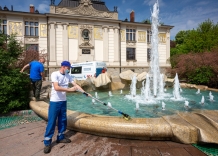Dwóch pracowników wykonuje prace porządkowe przy fontannie na pl. Szczepańskim