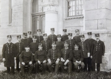 Zdjęcie czarno-białe. Pracownicy wodociągów w odświętnych mundurach przed wejściem do Dworca wodociągowego ul. Senatorska 1, 1914 rok.