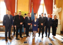 Zarząd Miasta Krakowa wraz z Przewodniczącym Rady Miasta Krakowa stoją na tle sztandaru.