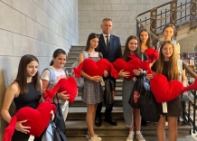 Grupa dziewczyn stojąca na schodach z pluszowymi czerwonymi sercami z rękami